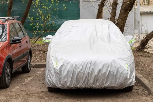A car covered with a tarp sits in a vehicle storage parking spot at a storage facility. 
